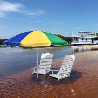 Two sun beds under the colorful umbrella in the shallow water