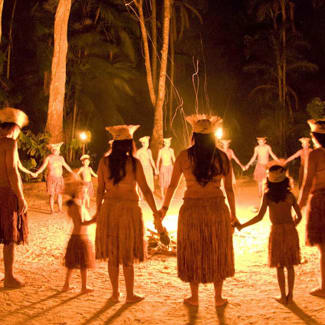 People in traditional outfits standing in a circle around the fire
