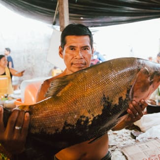 Man holding up a large fish in the market