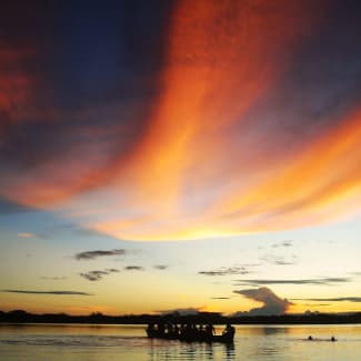 Sunset on the Amazon river and a small boat